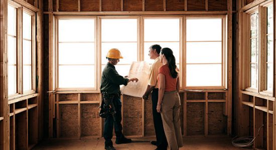 Couple qui regarde les plans de l'extension bois de leur maison avec l'architecte